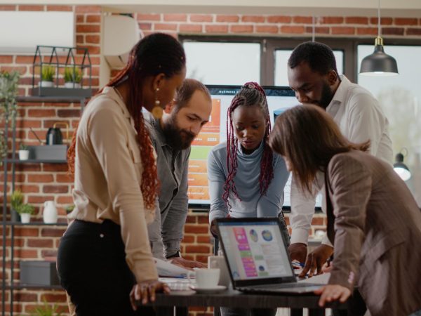 Team of colleagues analyzing charts on documents to plan project, working together to design presentation for business groth and development. Group of coworkers doing teamwork at company job.